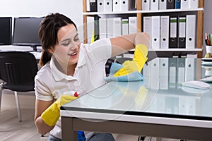 Woman Cleaning The Glass Office Desk With Rag