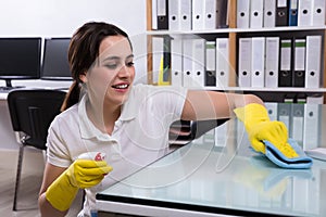 Woman Cleaning The Glass Office Desk With Rag