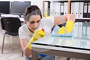 Woman Cleaning The Glass Office Desk With Rag