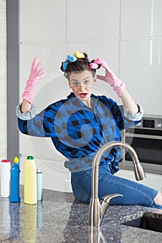 Woman IN a cleaning gloves sitting on a kitchen worktop