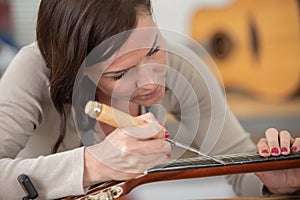 woman cleaning guitar in guitar maker workshop photo