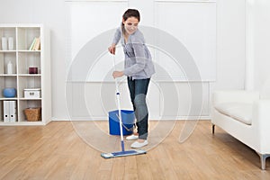 Woman cleaning hardwood floor of living room