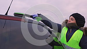 Woman cleaning her car on road in winter day