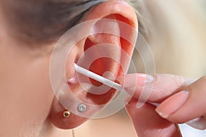 Woman cleaning her ear with cotton swab, people hygiene concept.