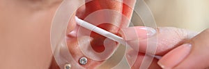 Woman cleaning her ear with cotton swab, people hygiene concept.