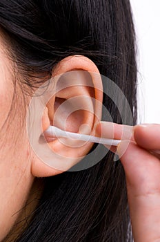 Woman is cleaning her ears with white cotton bud