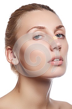 Woman cleaning her face. Beautiful young woman with clear-up patches or plaster on her nose looking at camera. Skin care concept