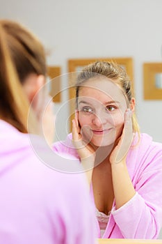 Woman cleaning her face with scrub in bathroom.
