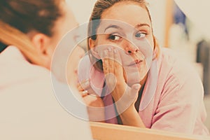 Woman cleaning her face with scrub in bathroom.