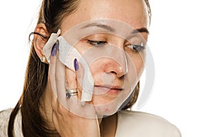 A woman cleaning her face with wet wipe on white