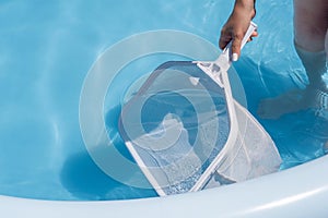 Woman cleaning her home's pool with a net