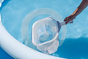 Woman cleaning her home& x27;s pool with a net