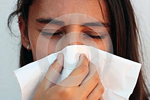 Woman cleaning her nose with a tissue on a white background