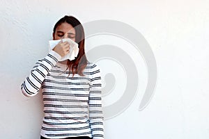 Woman cleaning her nose with a tissue on a white background