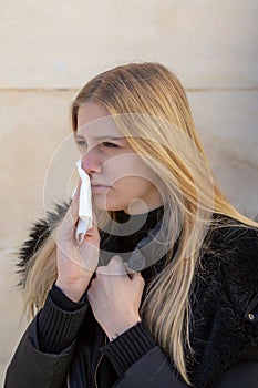 Woman cleaning her nose in winter