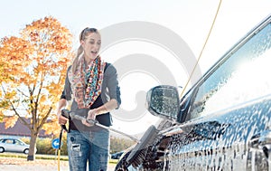 Woman cleaning her vehicle in self-service car wash