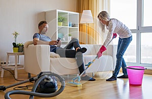 Woman cleaning home and man doesn`t help her photo