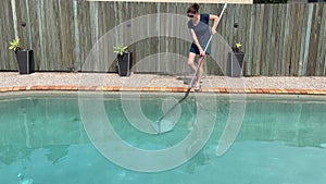 Woman cleaning home swimming pool