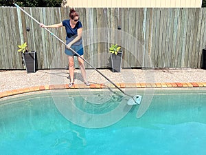 Woman cleaning home swimming pool
