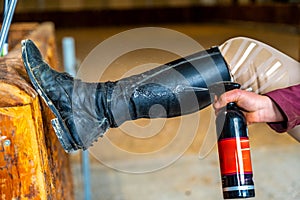 Woman cleaning horse riding boots with spray