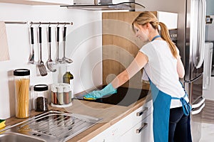 Woman Cleaning Induction Stove In Kitchen