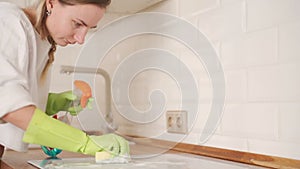 Woman Cleaning Induction Stove In Kitchen With Spray Bottle And Sponge