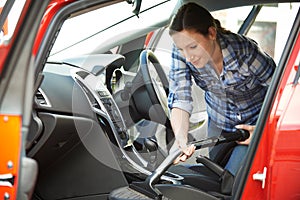 Woman Cleaning Interior Of Car Using Vacuum Cleaner