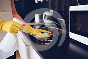 Woman cleaning kitchen cabinets with sponge