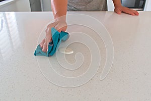 Woman cleaning kitchen countertop.