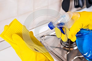 Woman cleaning a kitchen worktop with spray deterget and cleaning sponge