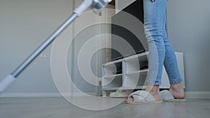 Woman cleaning living room with modern white upright vacuum cleaner