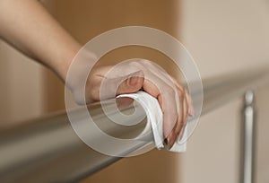 Woman cleaning metal railing with antiseptic wipe, closeup photo