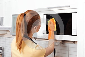 Woman cleaning microwave oven with rag