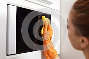 Woman cleaning microwave oven with rag