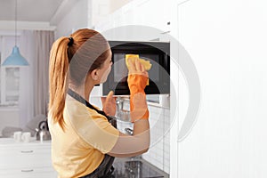 Woman cleaning microwave oven with rag