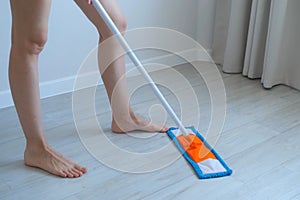 Woman is cleaning and mopping the linoleum floor, legs close-up.