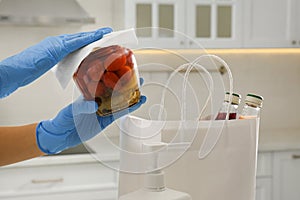 Woman cleaning newly purchased jar of pickled tomatoes with antiseptic wipe indoors, closeup. Preventive measures during COVID-19 photo