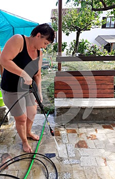 Woman Cleaning outside floor with water pressure cleaner