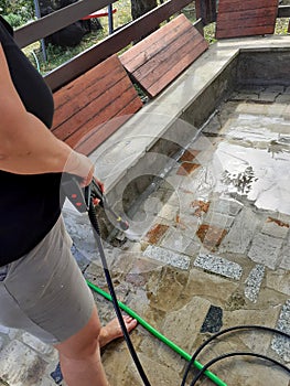 Woman Cleaning outside floor with water pressure cleaner