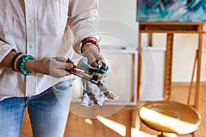 Woman cleaning paintbrush during working on her abstract paintings at studio