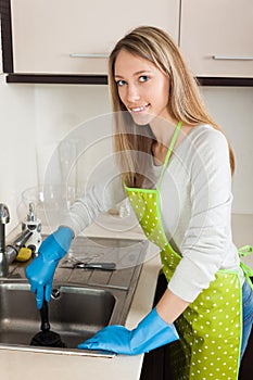 Woman cleaning pipe with plunger