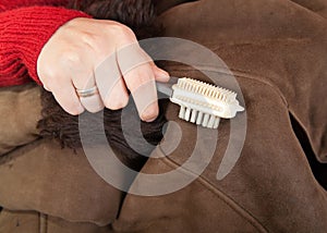 Woman cleaning a sheepskin with whisk broom