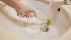 Woman is cleaning sink with brush, hand closeup.