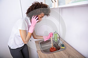Woman Cleaning Sink With Cup Plunger