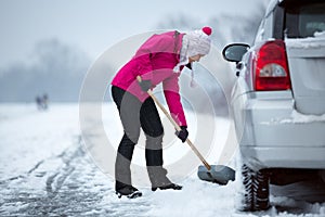 Woman cleaning snow around her car