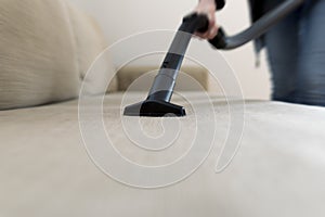 Woman cleaning the sofa, couch with vacuum cleaner