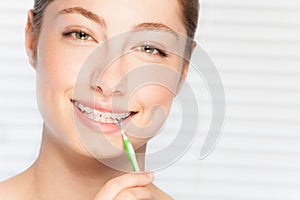 Woman cleaning teeth brace by interdental brush