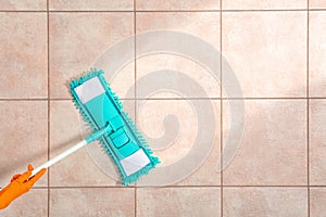 Woman cleaning tile floor with mop, top view.