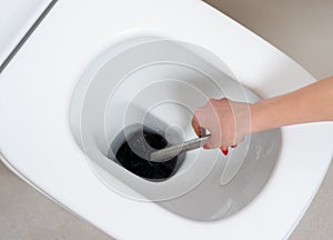 Woman cleaning the toilet bawl with a brush