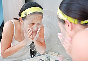 Woman cleaning washing her face reflect with bathroom mirror